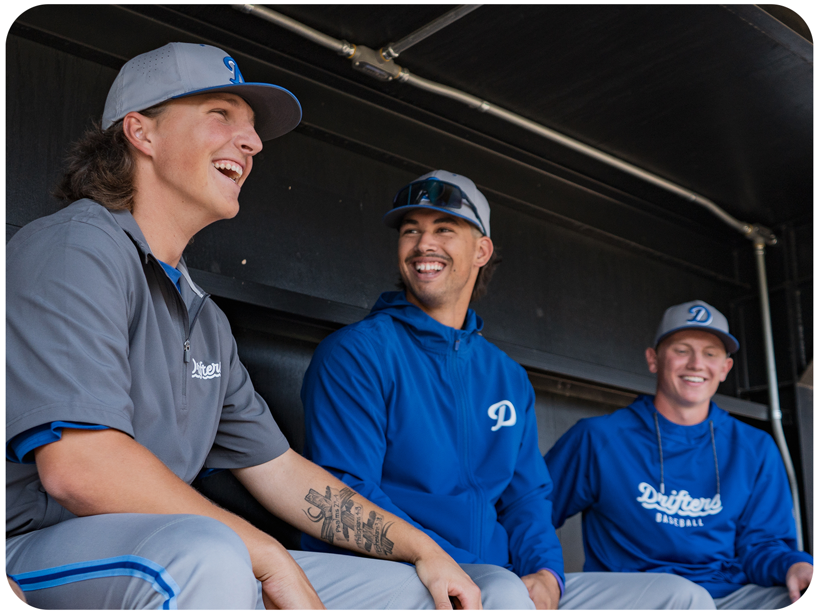 A selection of sports warm-up apparel showing baseball players in a dugout with team branding.